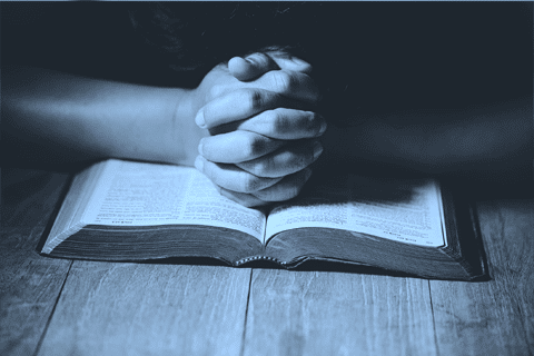 praying hands over a bible
